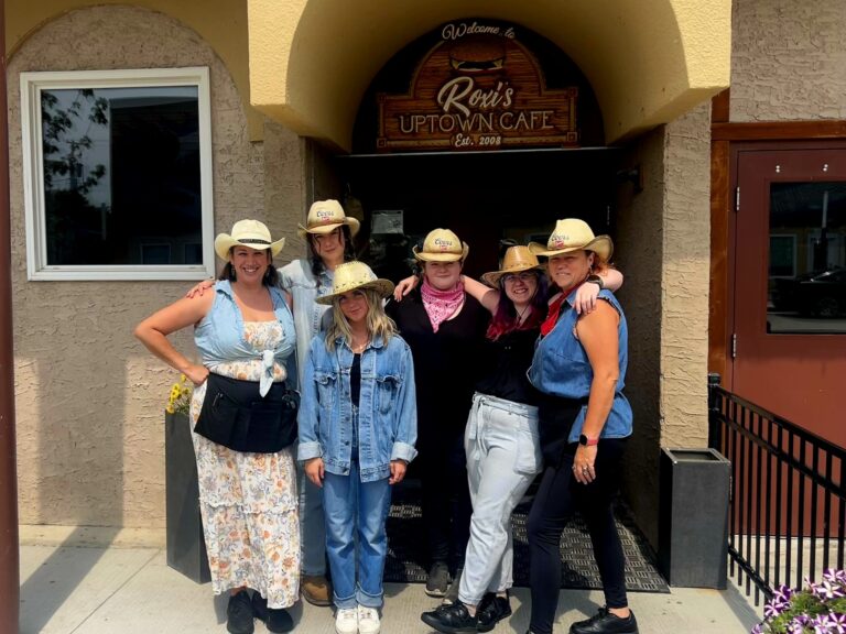 Employees of Roxies Uptown Cafe standing in western attire outside the front doors of the restaurant.