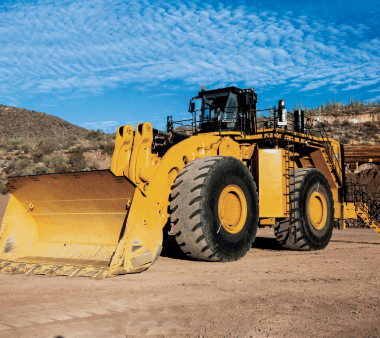 Loader truck on muddy terrain under a blue sky.